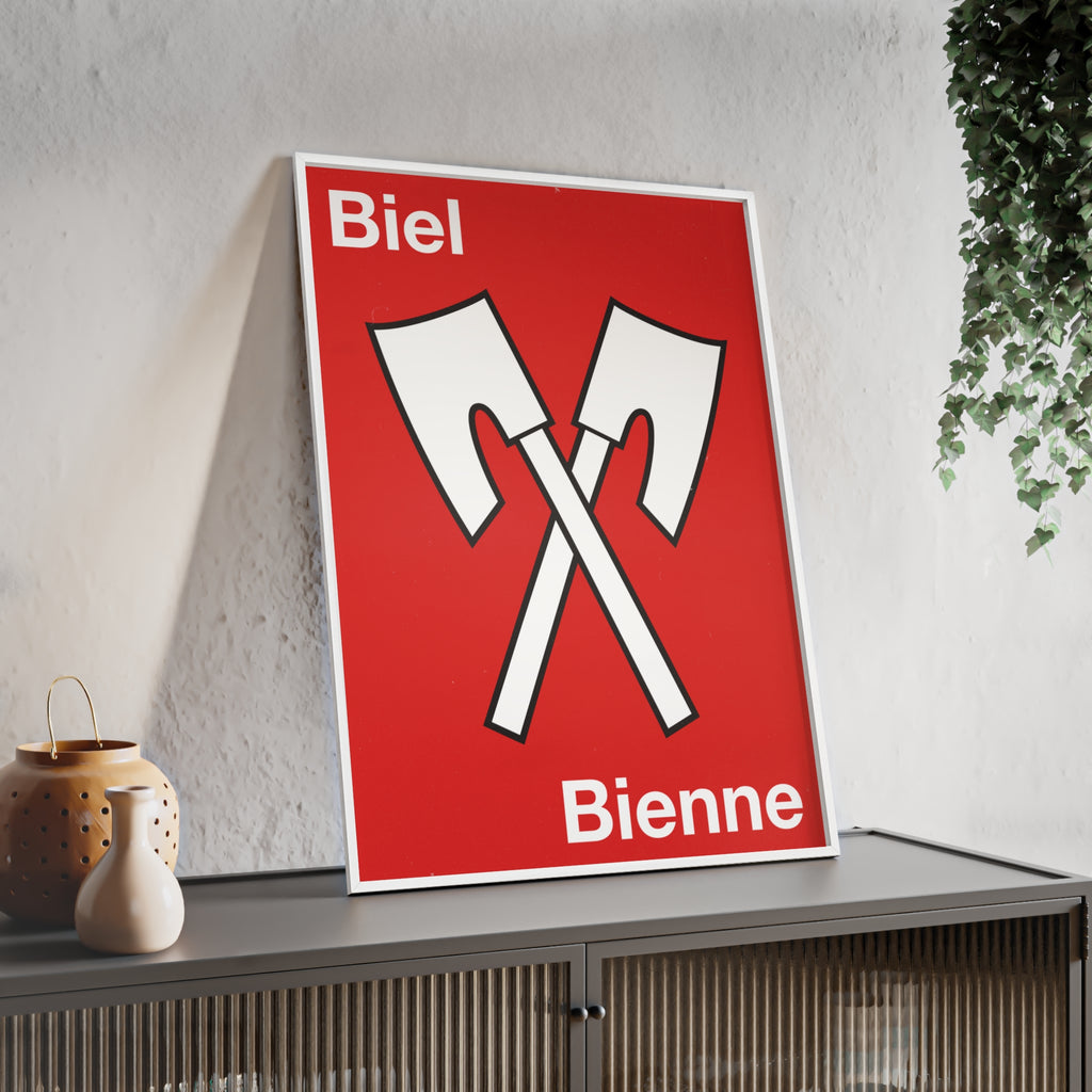 Minimalist framed wall poster of the Biel Bienne coat of arms featuring crossed white axes on a red background, displayed in a natural pinewood frame.