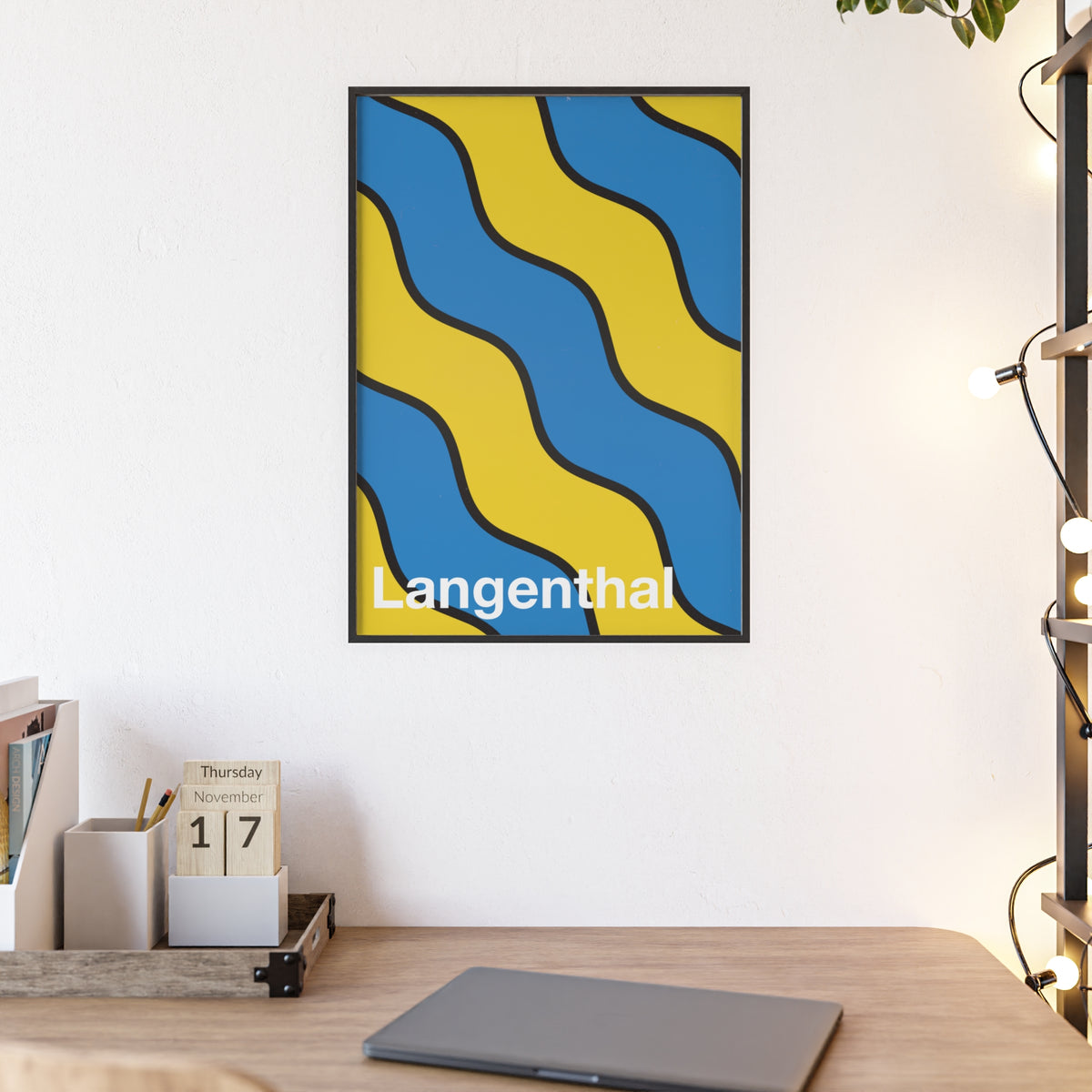 Minimalist framed poster of the Langenthal coat of arms featuring blue and yellow wavy stripes, set in a natural wood frame on an interior console table.