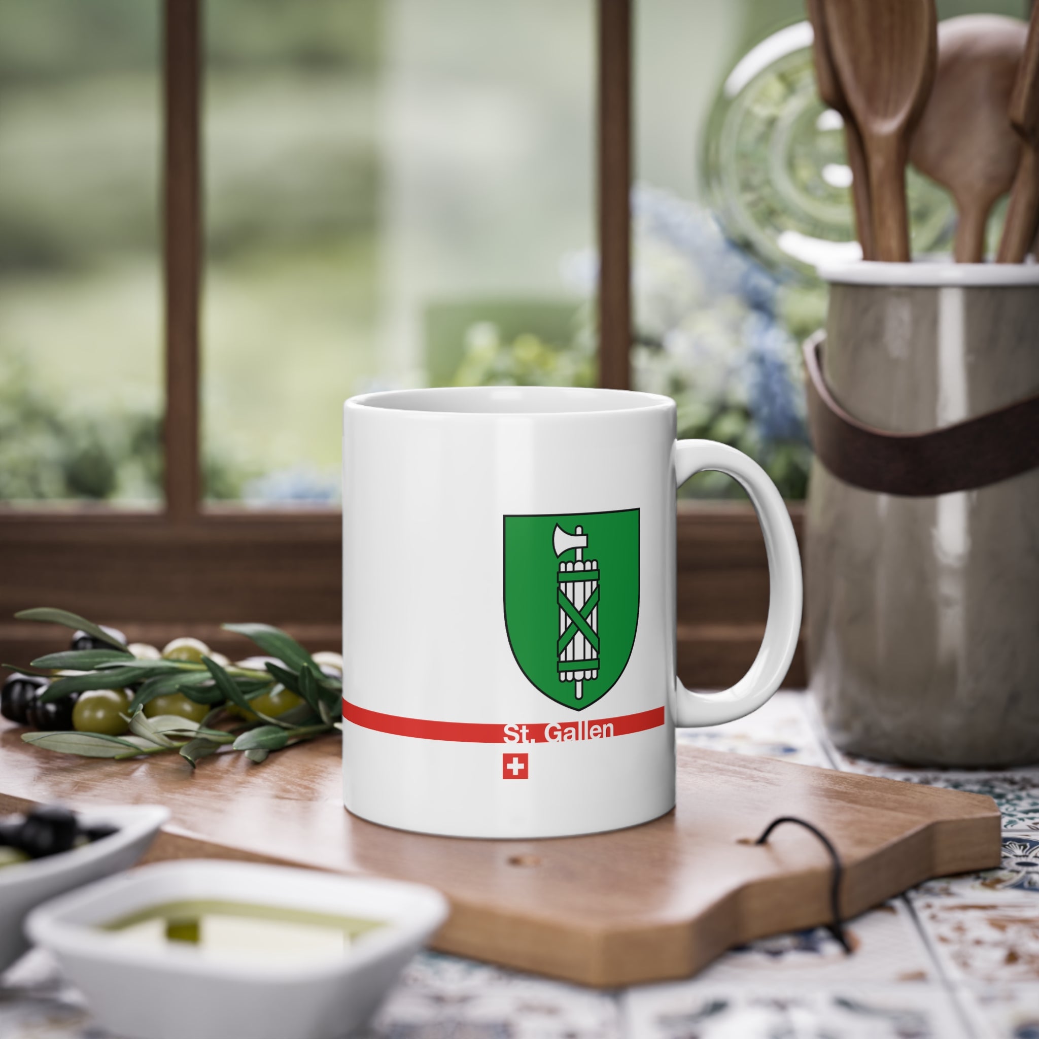 White ceramic mug featuring the green and silver Canton of St. Gallen coat of arms (fasces), a modern red horizontal line with 'St. Gallen' text, and a small Swiss cross below.