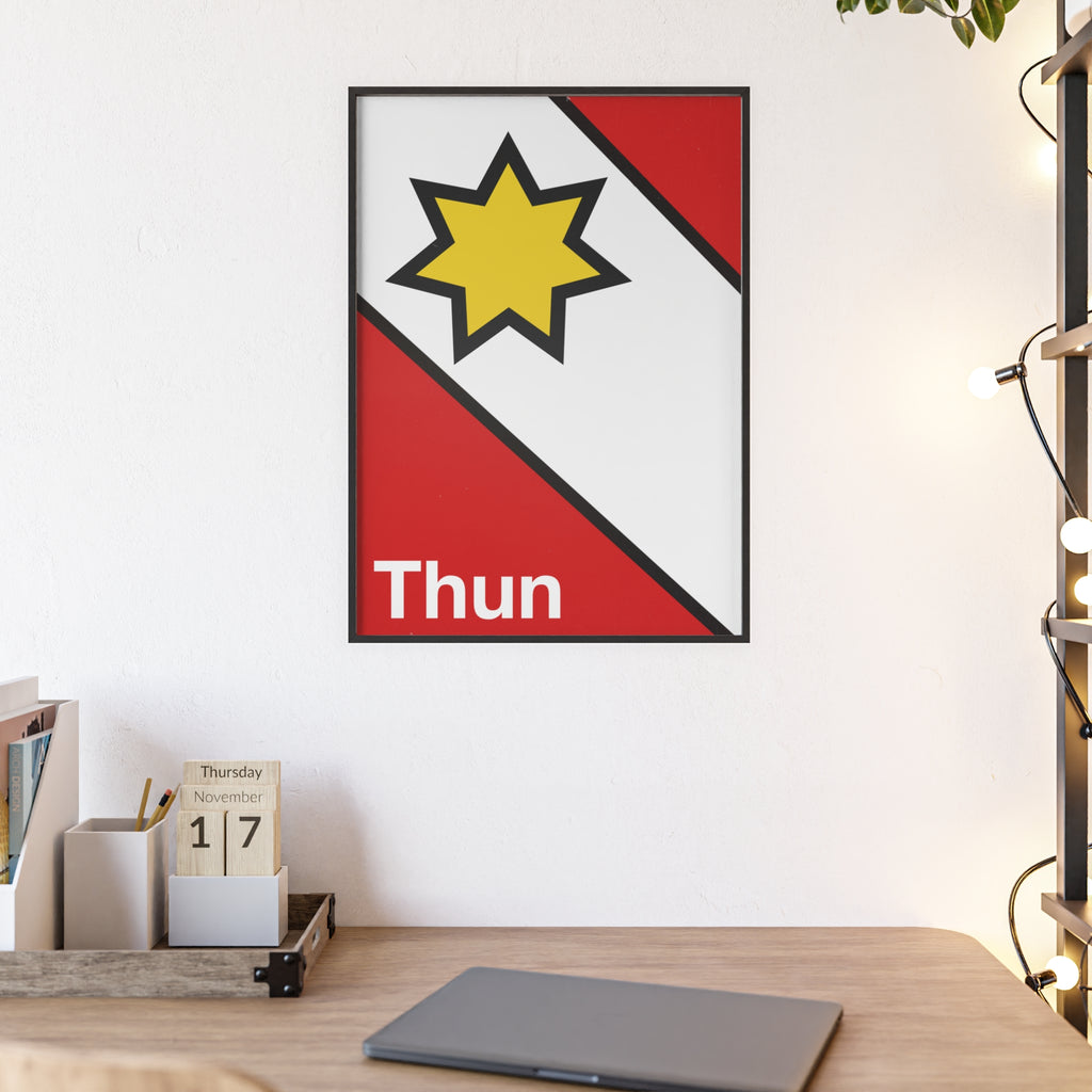 Minimalist framed poster of the Thun coat of arms featuring a yellow star on red and white diagonal fields, displayed in a natural wood frame on a console table.