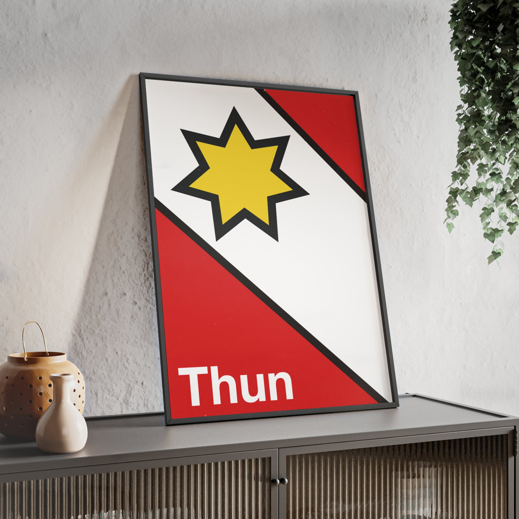 Minimalist framed poster of the Thun coat of arms featuring a yellow star on red and white diagonal fields, displayed in a natural wood frame on a console table.