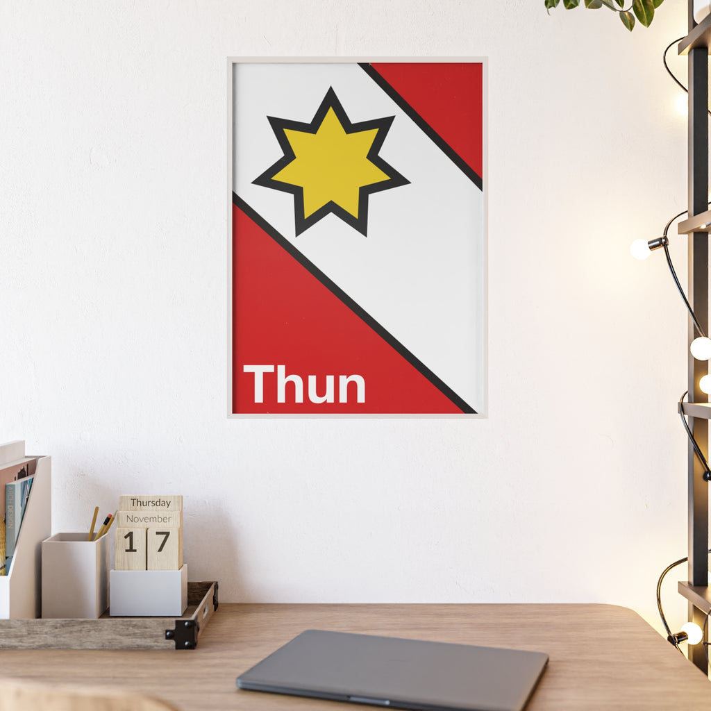Minimalist framed poster of the Thun coat of arms featuring a yellow star on red and white diagonal fields, displayed in a natural wood frame on a console table.