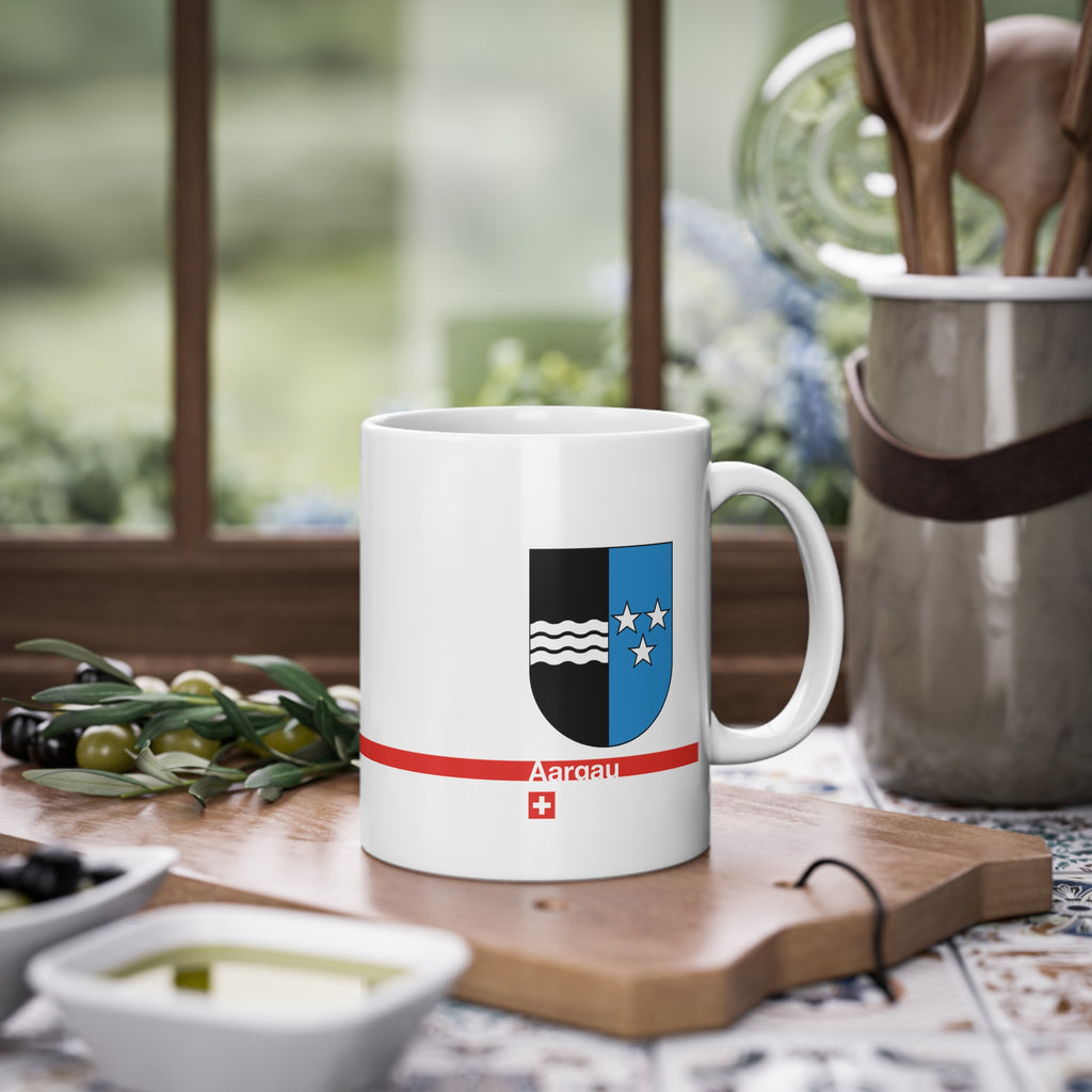 White ceramic mug with the vertically divided coat of arms of the Canton of Aargau (black with silver waves and blue with stars), featuring a modern red line and a small Swiss cross.