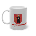 White ceramic mug with the red Canton of Glarus coat of arms featuring Saint Fridolin, a modern red line with 'Glarus' text and a small Swiss cross.