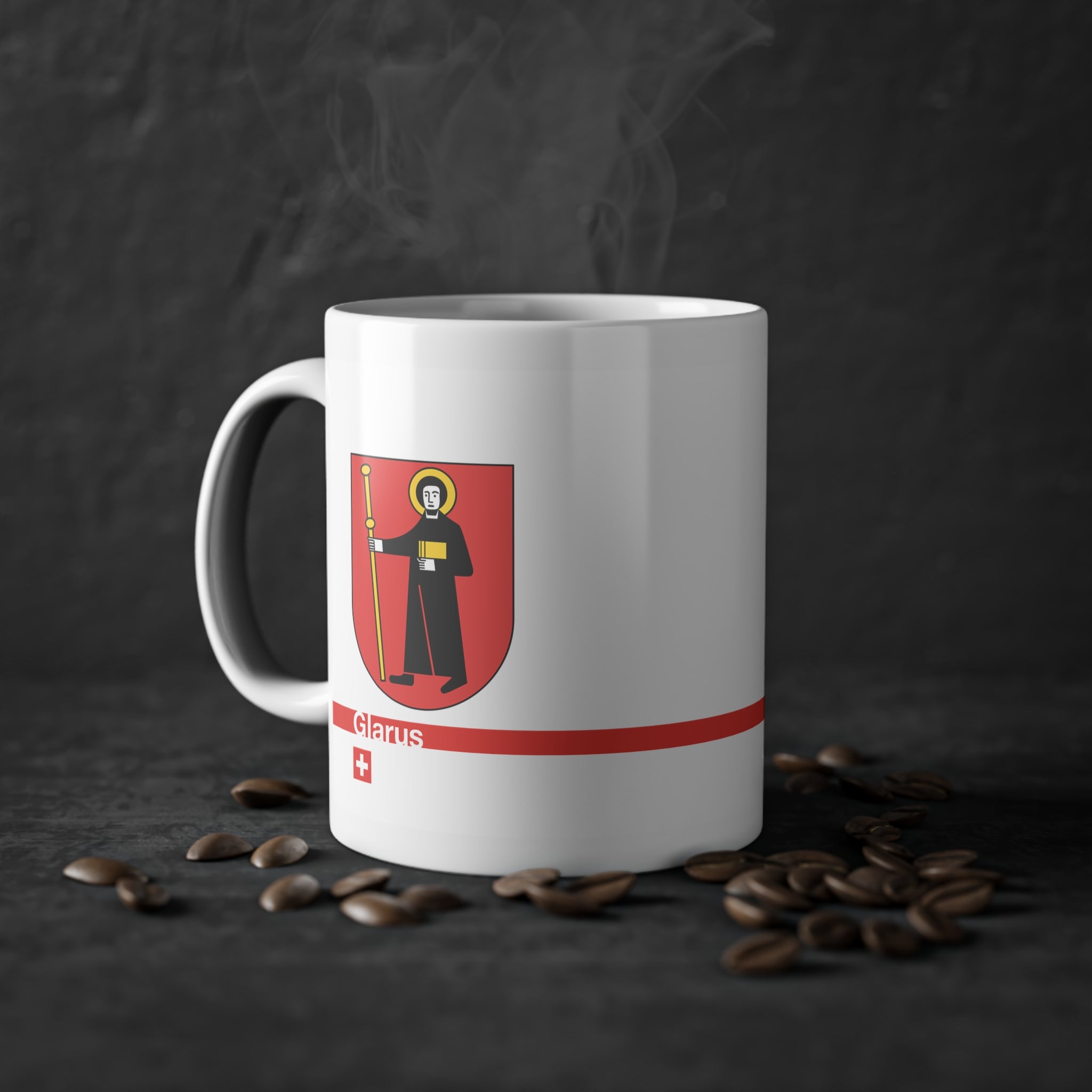 White ceramic mug with the red Canton of Glarus coat of arms featuring Saint Fridolin, a modern red line with 'Glarus' text and a small Swiss cross.
