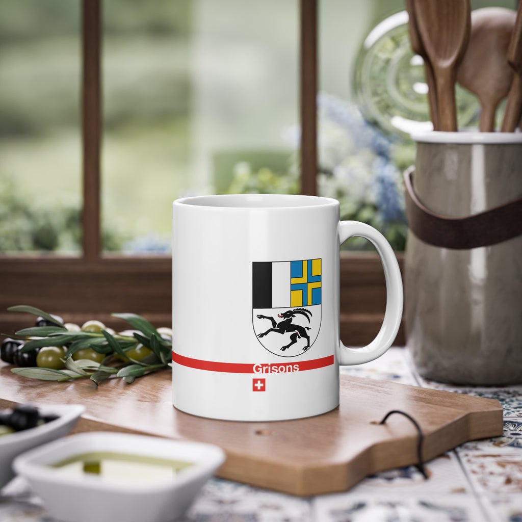 White ceramic mug with the Canton of Grisons (Graubünden) coat of arms featuring the black ibex, blue and yellow fields, a modern red line with 'Grisons' text, and a small Swiss cross.
