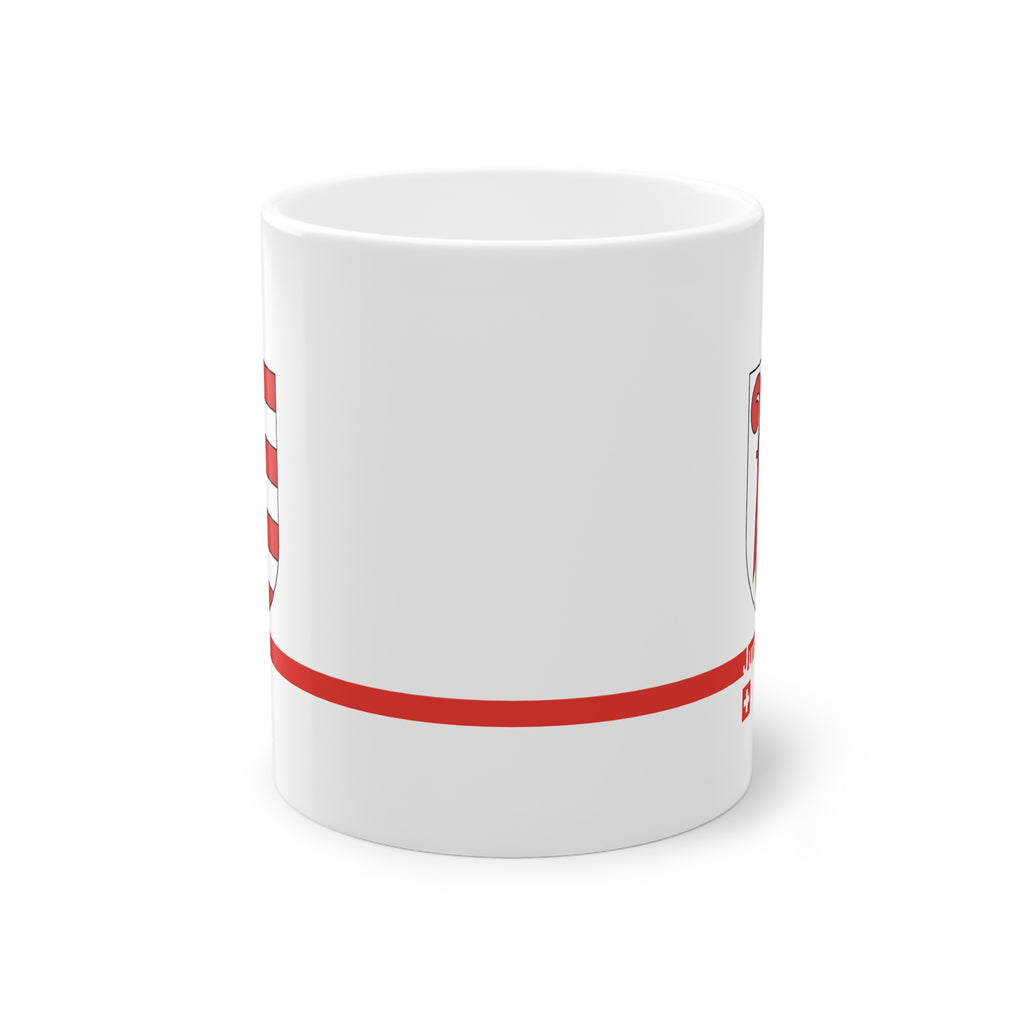 White ceramic mug featuring the red and white Canton of Jura coat of arms (bishop's crosier and seven stripes), a modern red horizontal line with 'Jura' text, and a small Swiss cross below.