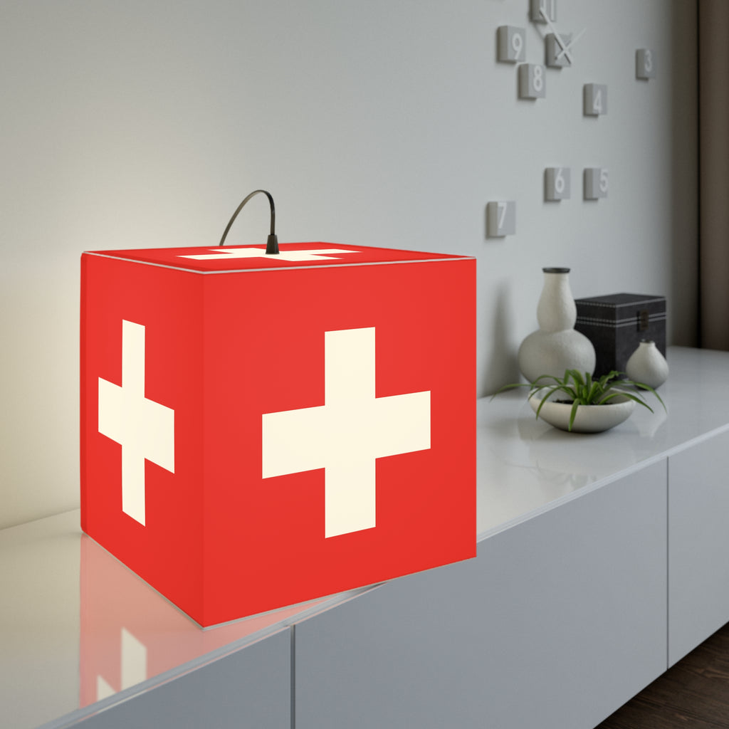 Minimalist cube-shaped lamp featuring the red and white Swiss cross flag design. Available in regular 30 cm and small 20 cm sizes, shown as a geometric lighting fixture with a matte finish, perfect for modern home decor and Swiss National Day 1st of August celebrations.