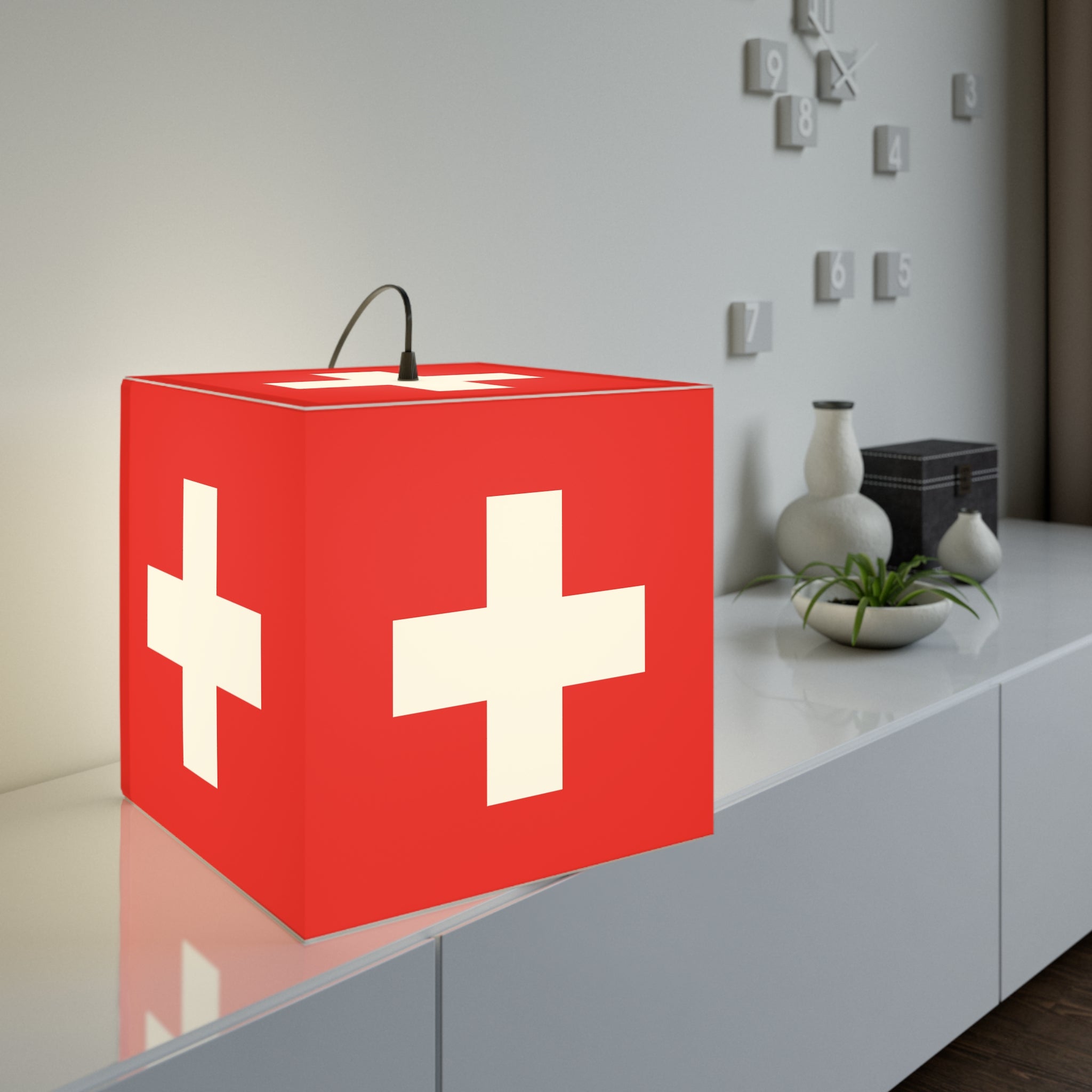 Minimalist cube-shaped lamp featuring the red and white Swiss cross flag design. Available in regular 30 cm and small 20 cm sizes, shown as a geometric lighting fixture with a matte finish, perfect for modern home decor and Swiss National Day 1st of August celebrations.