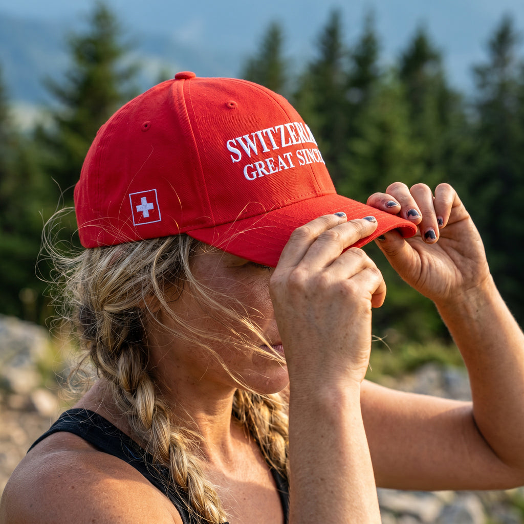 Product multi-angle mockup views of a premium red structured Swiss baseball cap. Front features white 'SWITZERLAND GREAT SINCE 1291' embroidery. Right side displays the Swiss cross flag, left side features country names in German, French, Italian, and Romansh, and the closed back shows a circular CH logo.