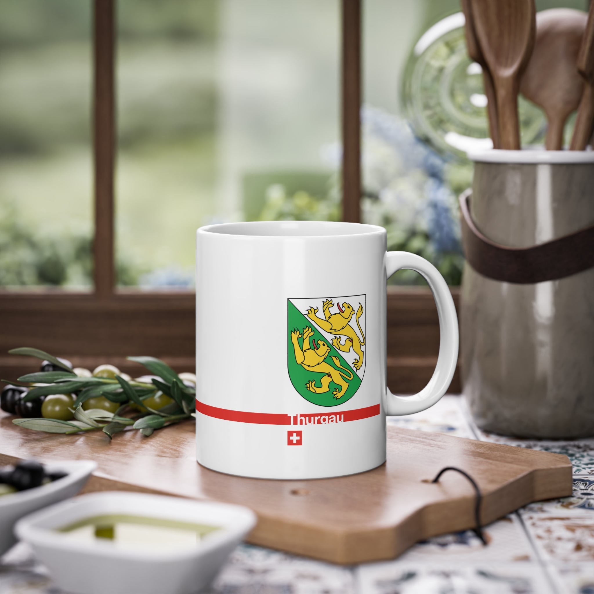 White ceramic mug featuring the green and white Canton of Thurgau coat of arms with two golden lions, a modern red horizontal line with 'Thurgau' text, and a small Swiss cross below.