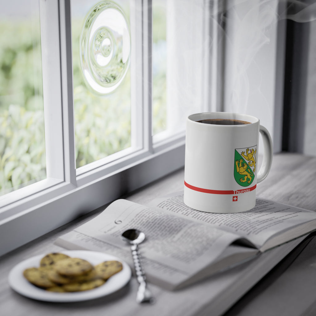 White ceramic mug featuring the green and white Canton of Thurgau coat of arms with two golden lions, a modern red horizontal line with 'Thurgau' text, and a small Swiss cross below.