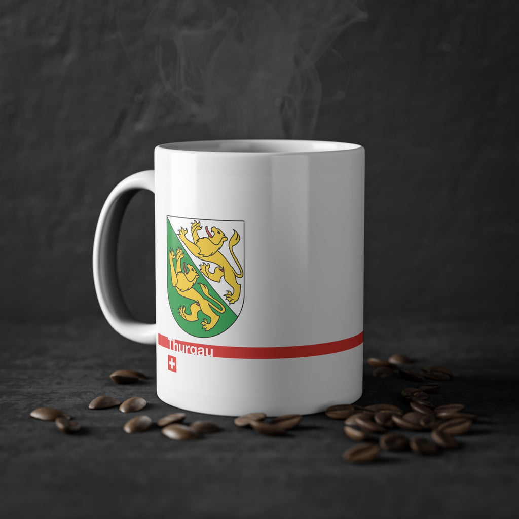 White ceramic mug featuring the green and white Canton of Thurgau coat of arms with two golden lions, a modern red horizontal line with 'Thurgau' text, and a small Swiss cross below.