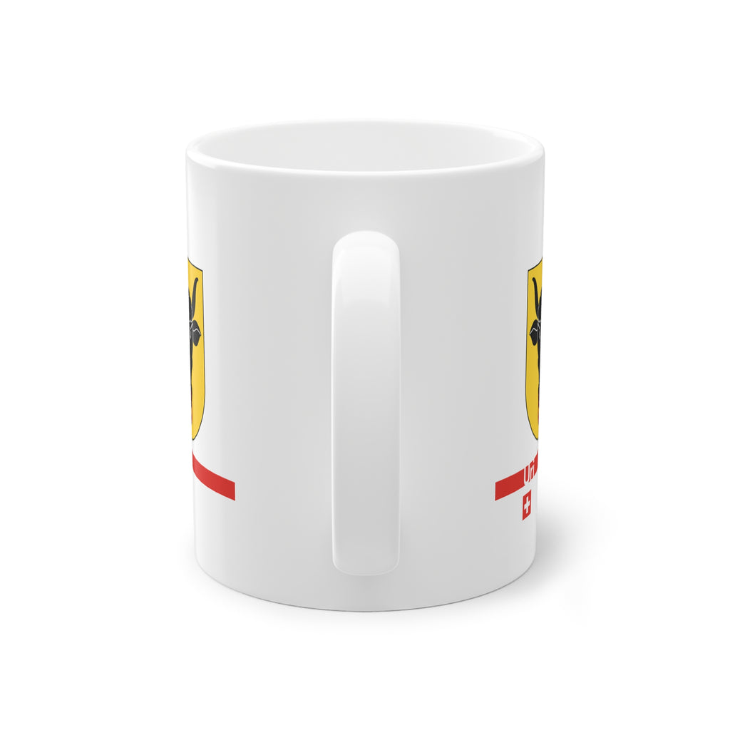 White ceramic mug featuring the golden Canton of Uri coat of arms with a black bull's head and red nose ring, a modern red horizontal line with 'Uri' text, and a small Swiss cross below.
