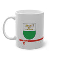 White ceramic mug featuring the white and green Canton of Vaud coat of arms with golden 'Liberté et Patrie' text, a modern red horizontal line with 'Vaud' text, and a small Swiss cross below.